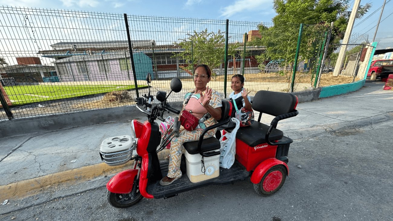 Abuelita lleva a nieta a la escuela en motocicleta de tres ruedas