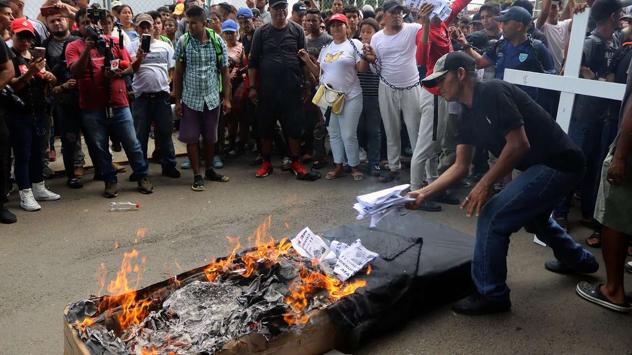Migrantes protestan con un ataúd y las manos encadenadas