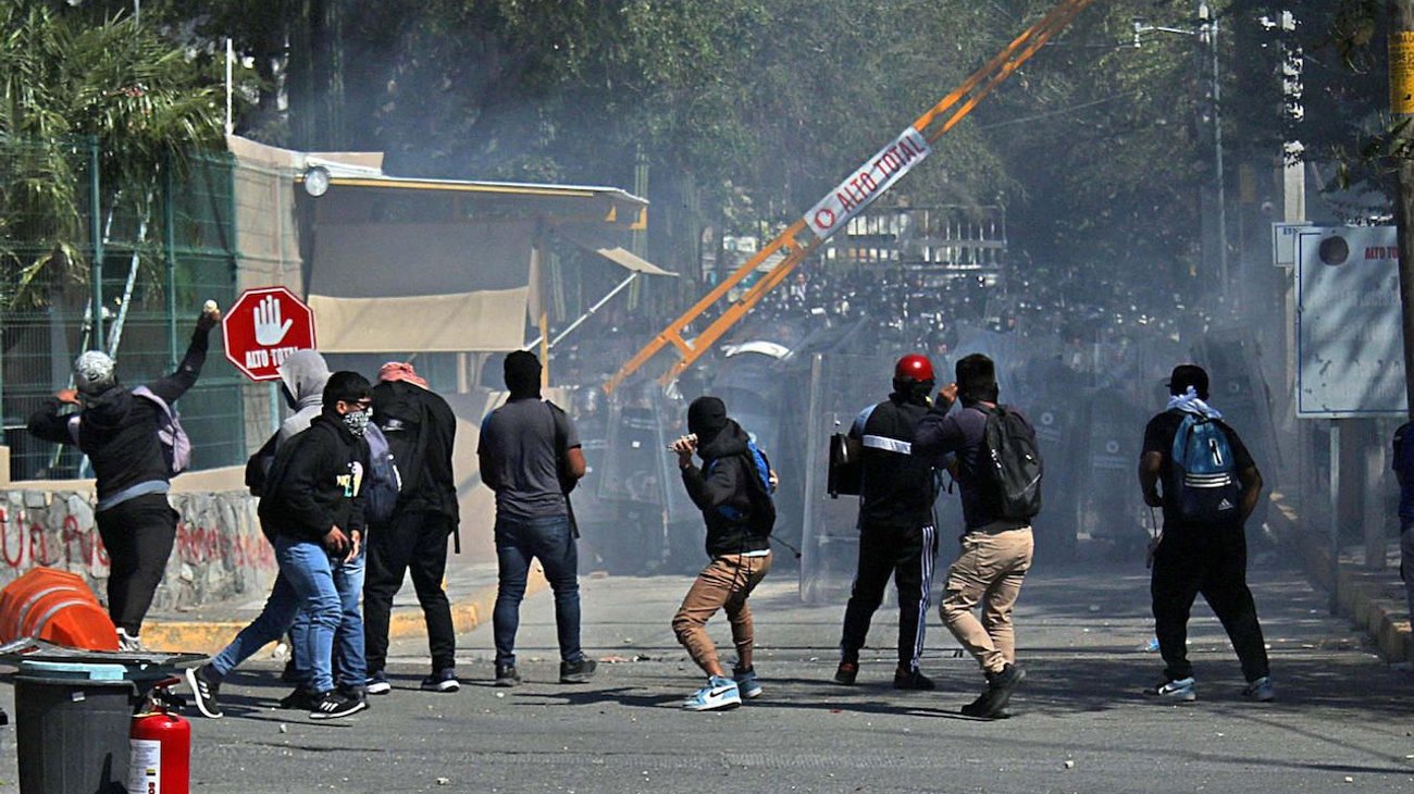 Protesta de Ayotzinapa deja agentes heridos y autos quemados