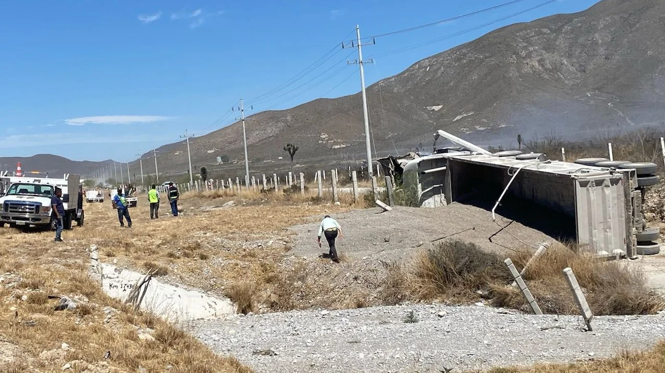 Vuelca tráiler cargado con arena y provoca incendio de maleza
